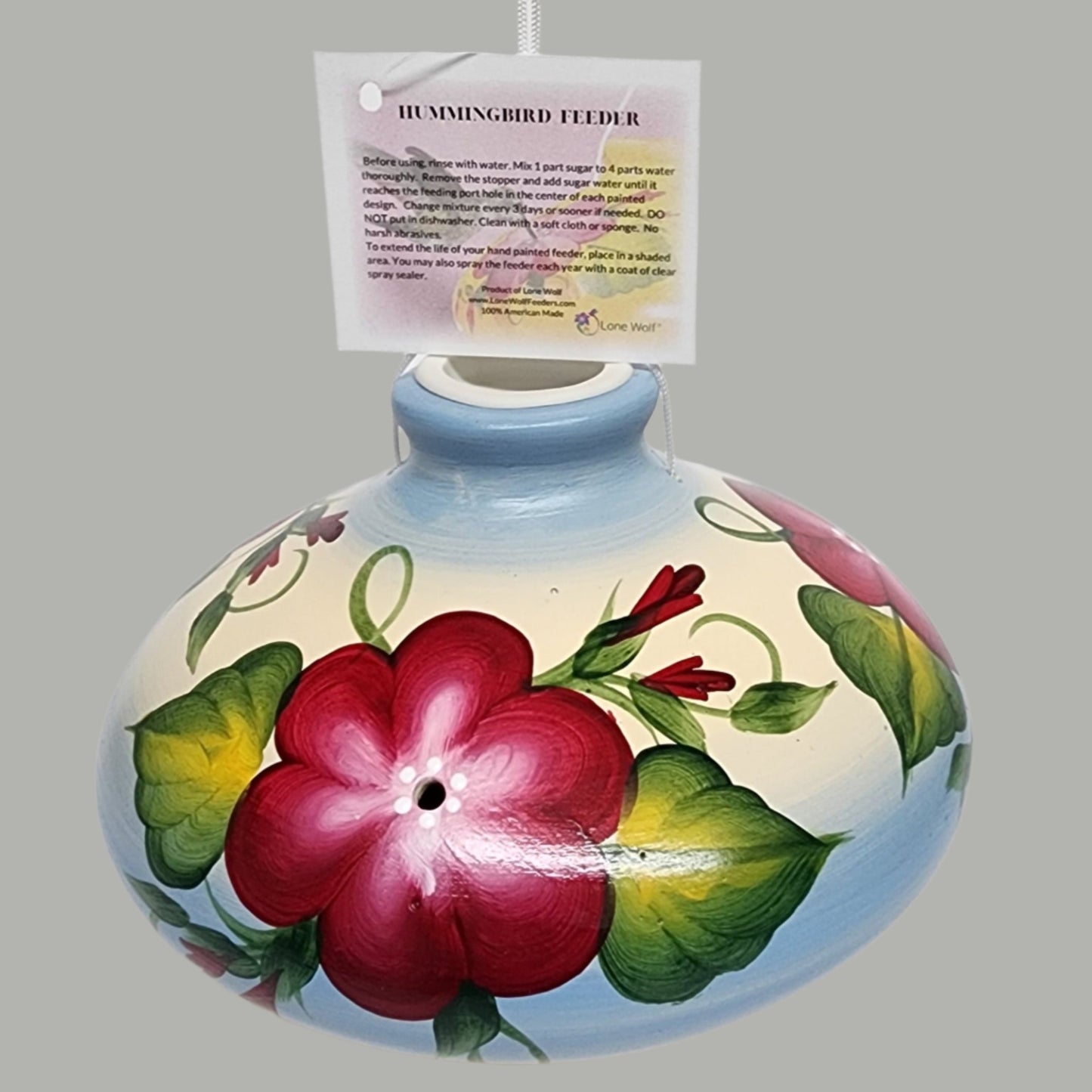 Red flowers with green leaves on ceramic blue and tan feeder