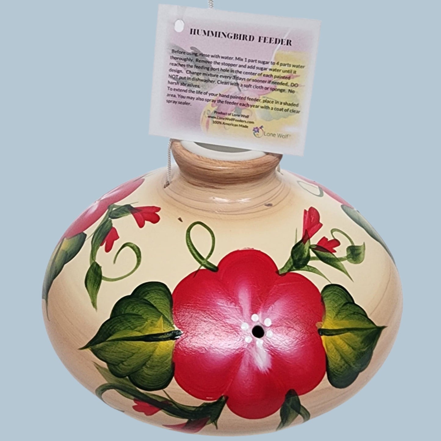 red flowers on a tan ceramic hummingbird feeder
