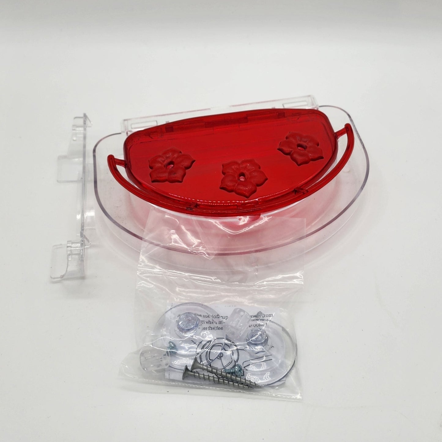 Red hummingbird feeder with clear attachments and moat