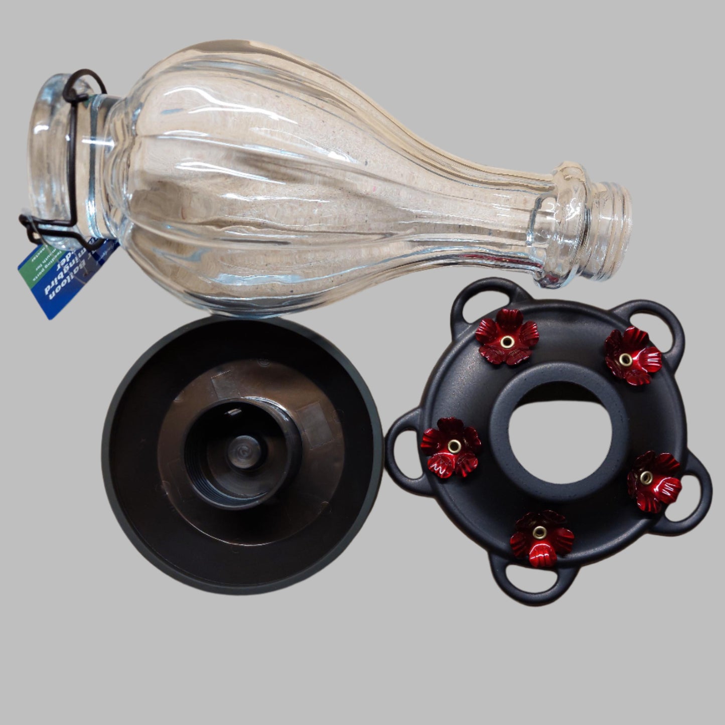 Clear balloon shaped bottle with 2 dark base pieces with red flowers