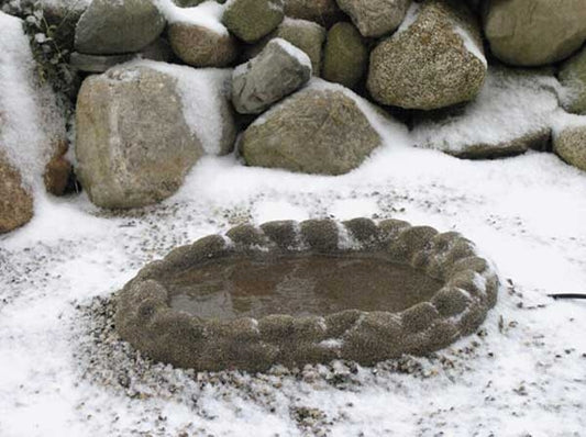 Brown coated fake rock birdbath sitting snow