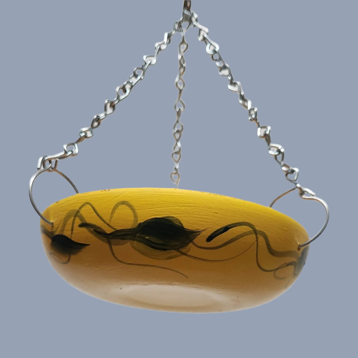 orange bowl with green leaves and silver hanging chains