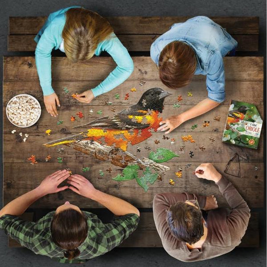 Four people working on a puzzle of a bird at a wooden table.