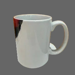 A white ceramic coffee mug with a handle, sitting on a white speckled countertop against a wooden paneled wall.