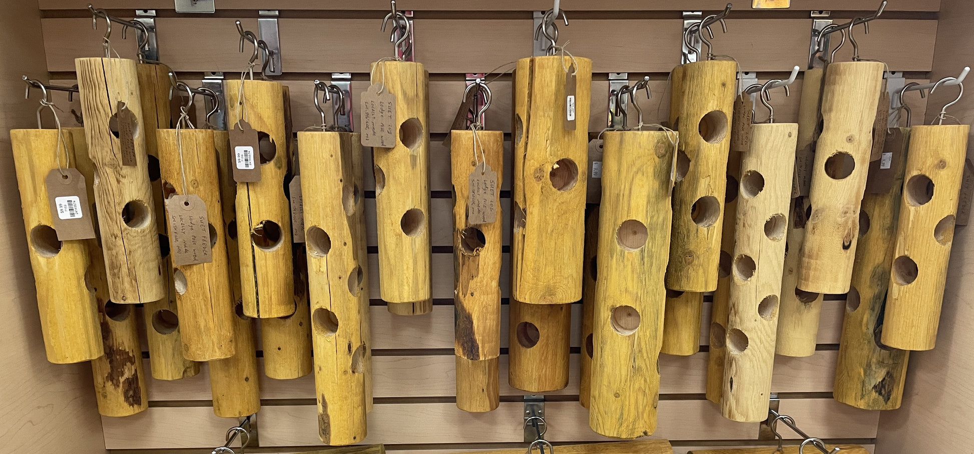 Wooden bird feeders with tags hanging on a wall