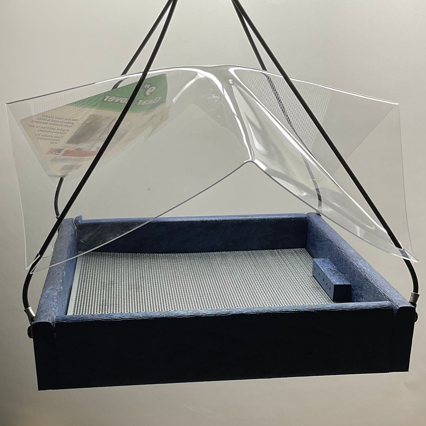 Clear plastic cover over a blue bird feeder on a white background