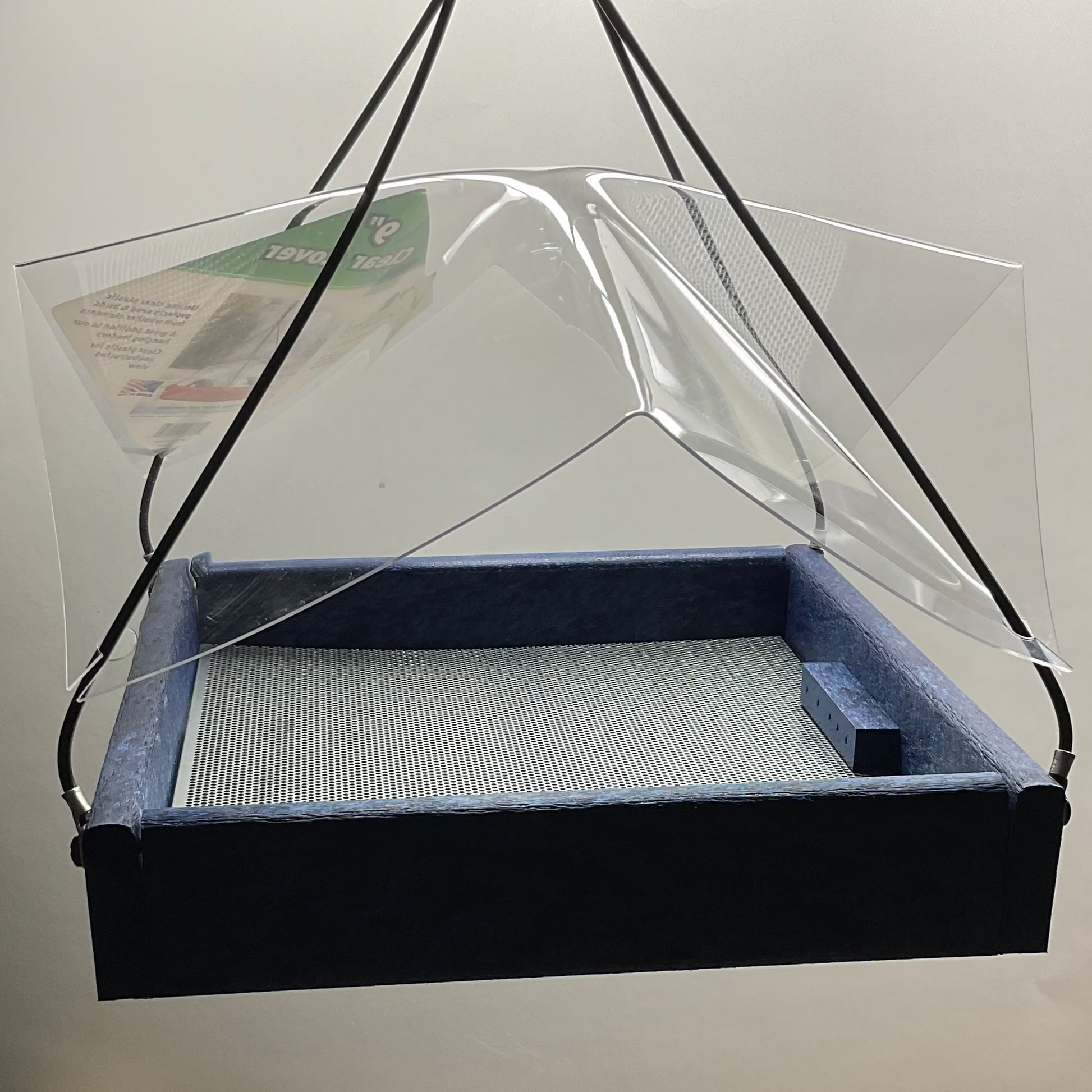 Clear plastic cover over a blue bird feeder on a white background