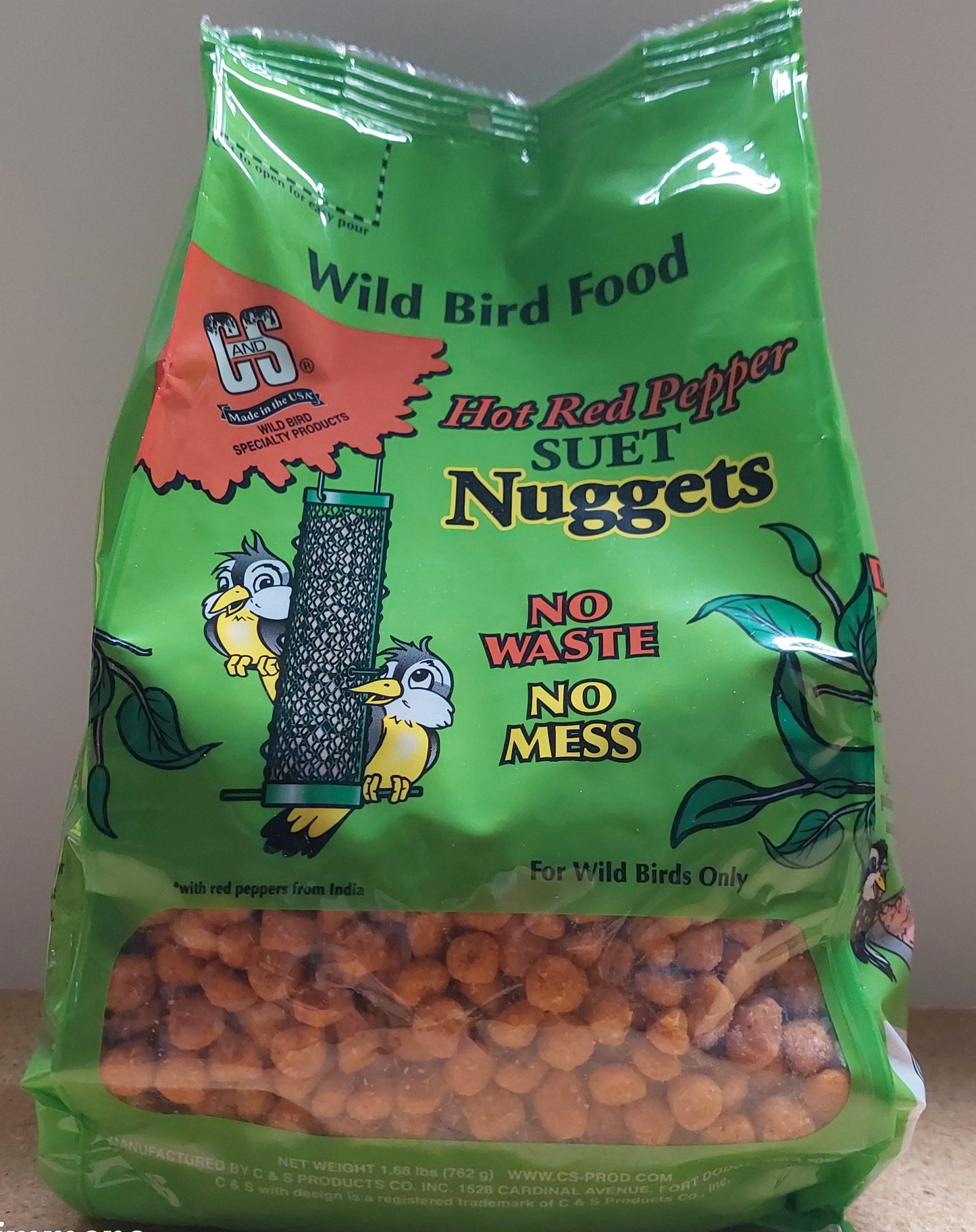 Green bag of Wild Bird Food with orange bird seeds on a neutral background