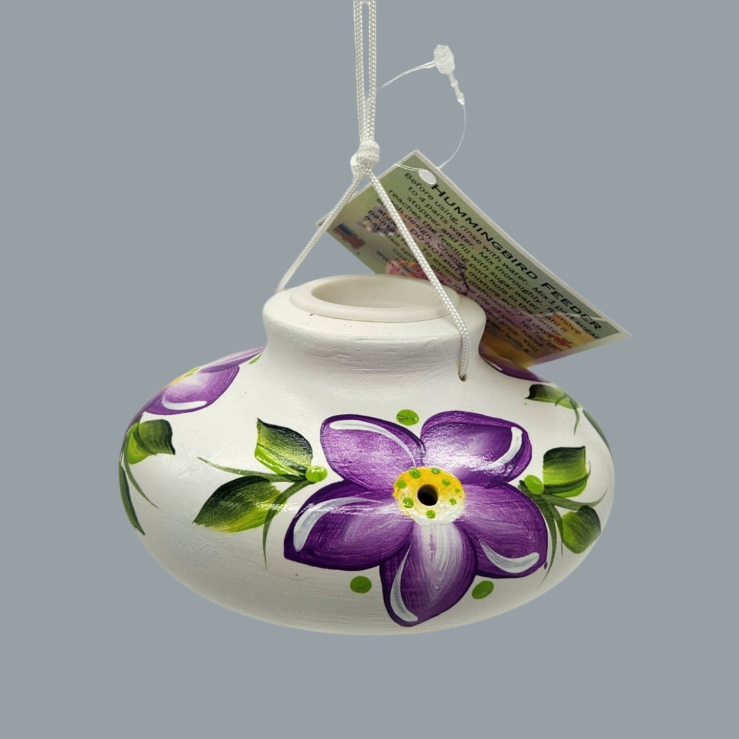 White ceramic feeder with purple flowers and green leaves