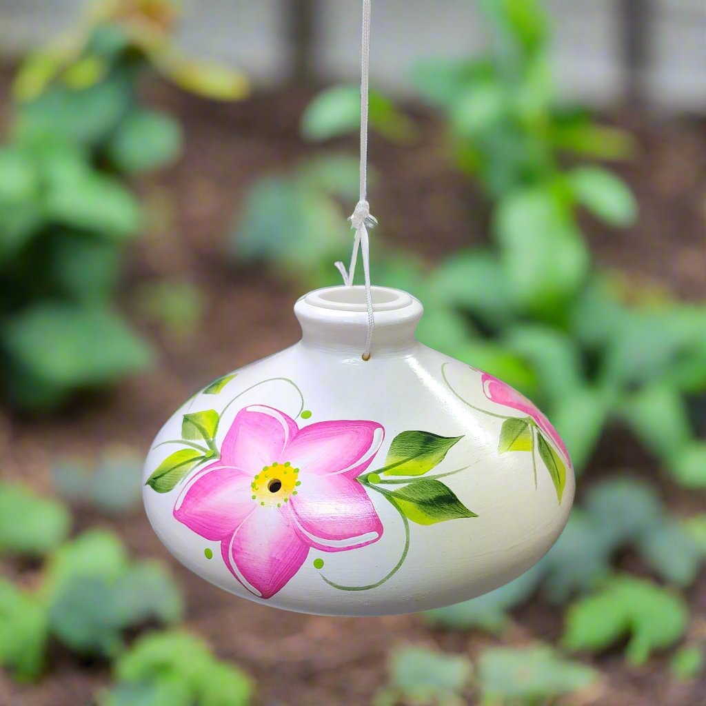 White ceramic feeder with fushia flowers an green leaves