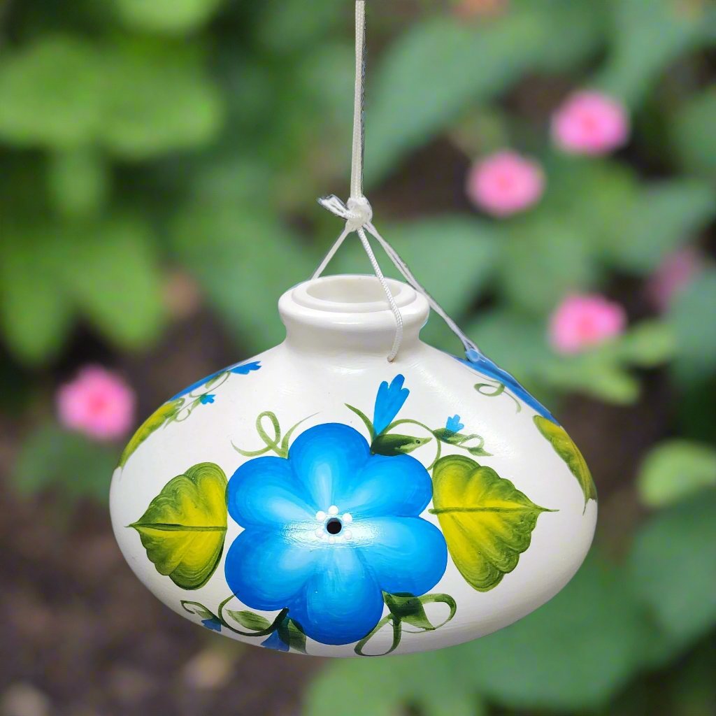 White ceramic feeder with blue flowers and green leaves