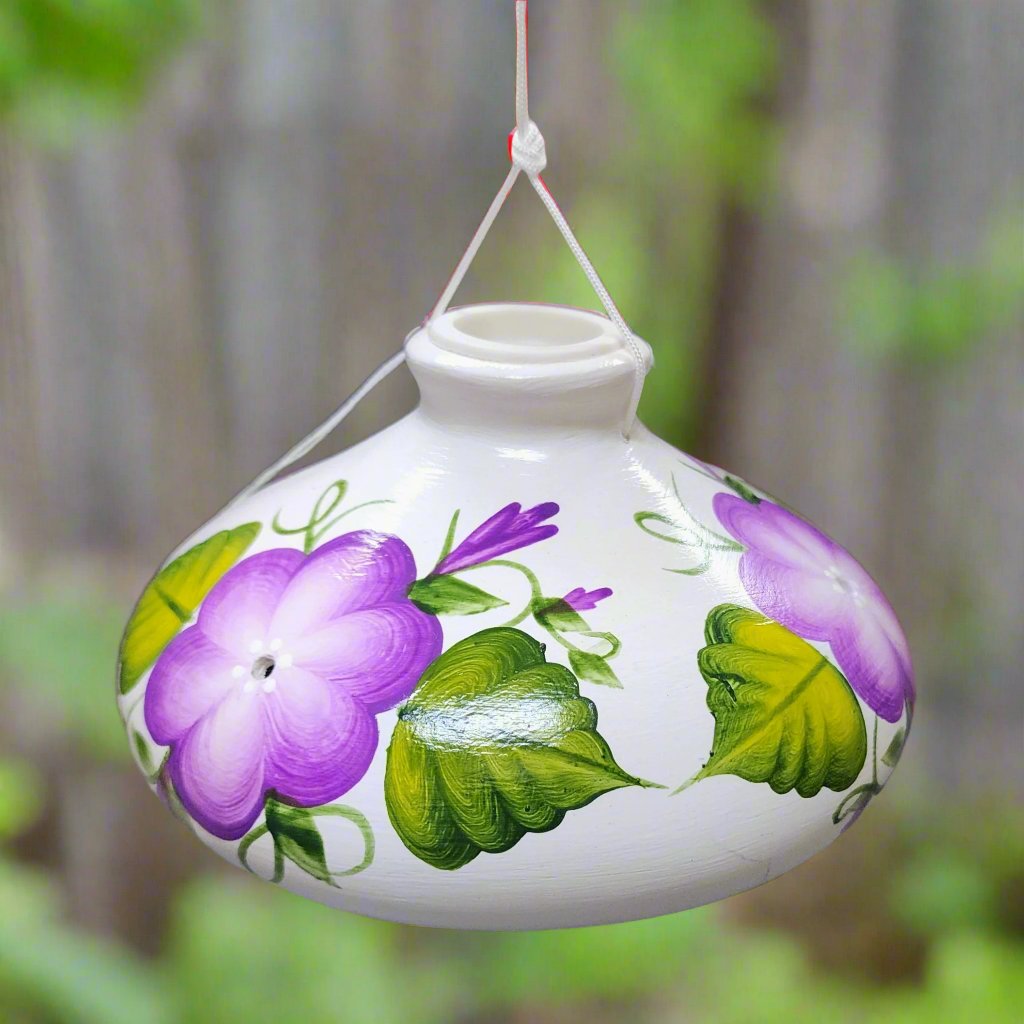 White ceramic feeder with purple flowers and green leaves