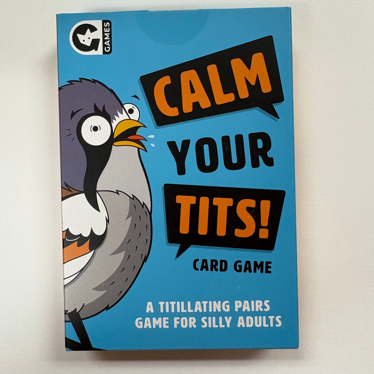 The front of a card game box titled 'Calm Your Tits!' by G Games, featuring a cartoon bird on a bright blue background with bold black and orange text.
